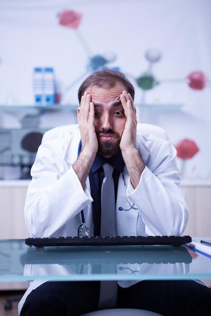 Foto retrato de un joven médico quemado en su gabinete de hospital. joven médico sobrecarga de trabajo en el gabinete del hospital.