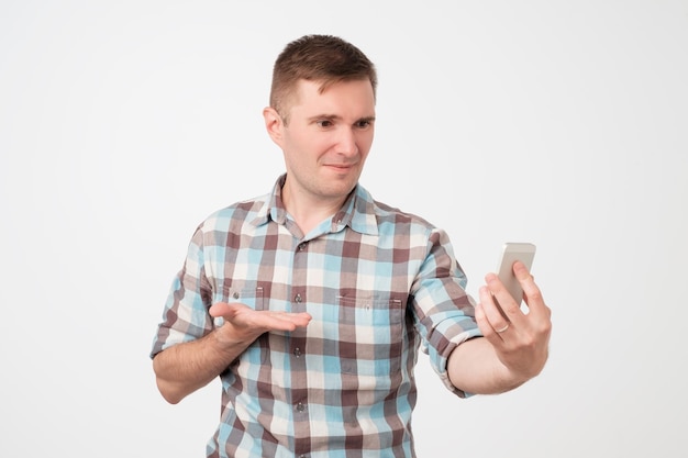 Retrato de un joven mirando su teléfono inteligente confundido