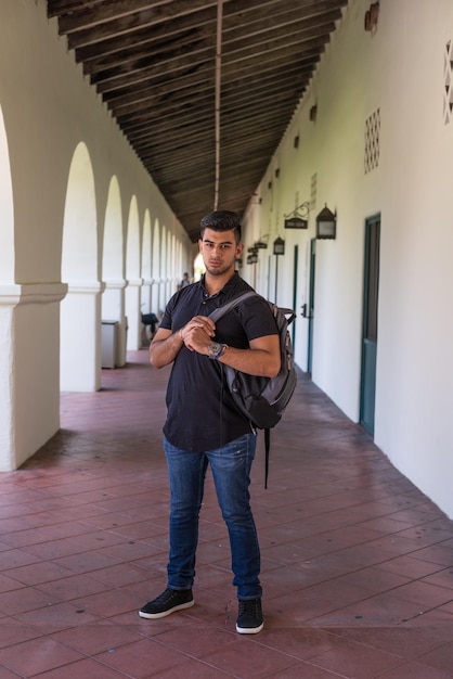 Retrato de un joven con una mochila en el pasillo