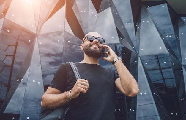 Retrato de un joven de moda hablando por teléfono en un hermoso fondo urbano oscuro