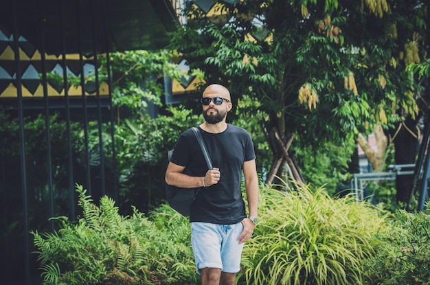 Retrato de un joven de moda en un hermoso fondo de hojas verdes en la jungla