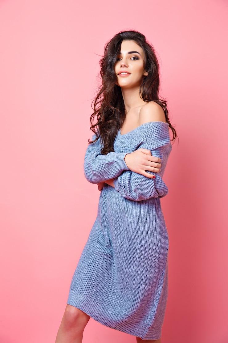 Foto retrato de joven modelo expresivo en suéter de punto azul sobre fondo rosa studio