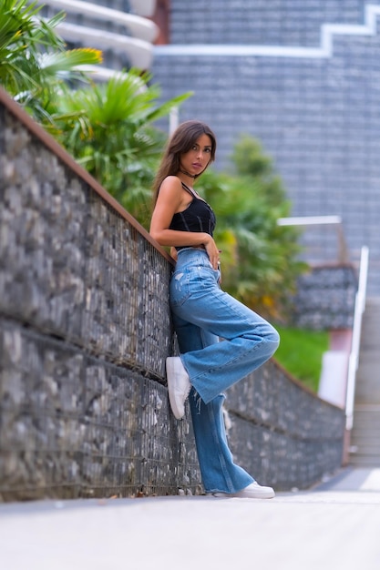 Retrato de una joven modelo morena con gorra negra y jeans en el estilo de vida de la ciudad