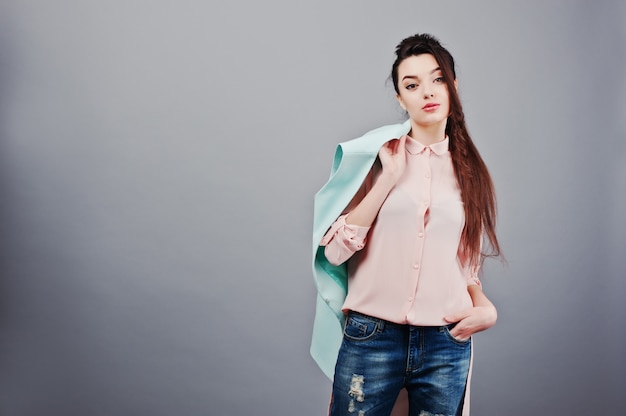 Retrato de joven morena con blusa rosa, chaqueta turquesa, jeans rotos