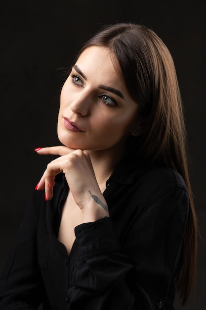 Retrato de una joven morena con cabello largo en el estudio Foto dramática en colores oscuros