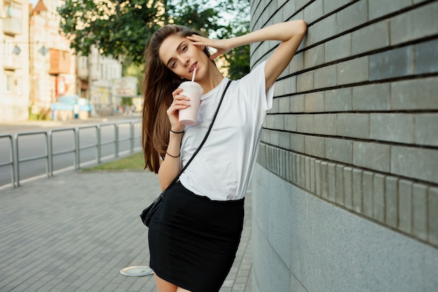 Retrato de una joven morena en una camiseta blanca con batido