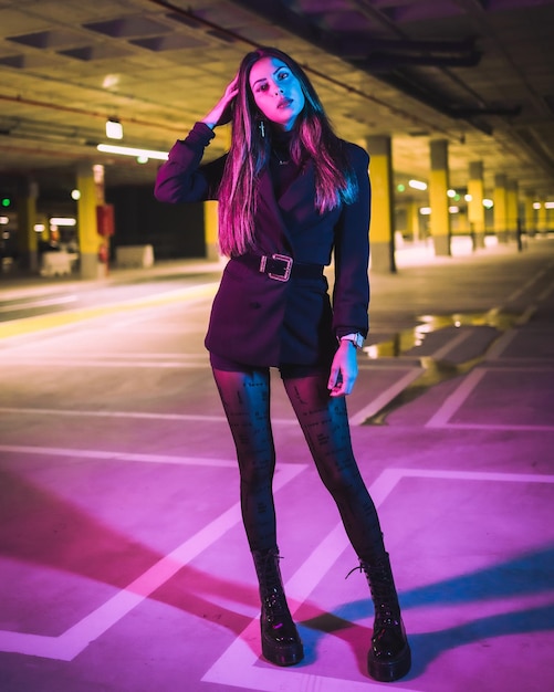 Retrato de una joven morena modelo caucásica por la noche en un estacionamiento subterráneo