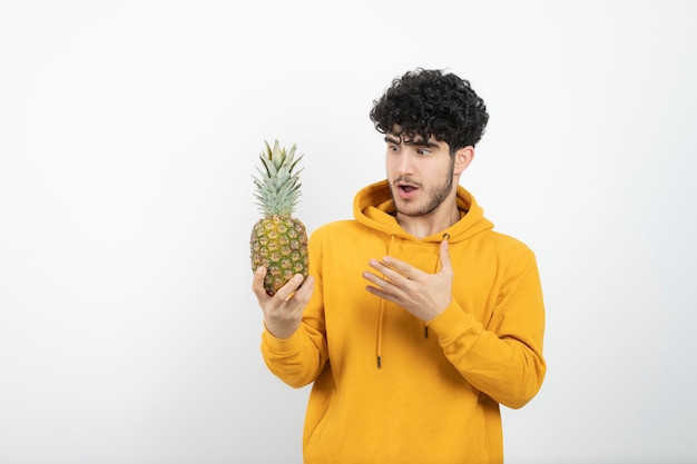 Retrato de un joven morena de pie y sosteniendo la piña.