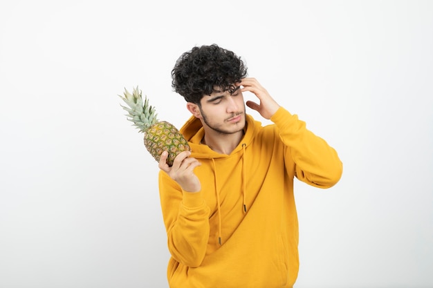 Retrato de un joven morena de pie y sosteniendo la piña.