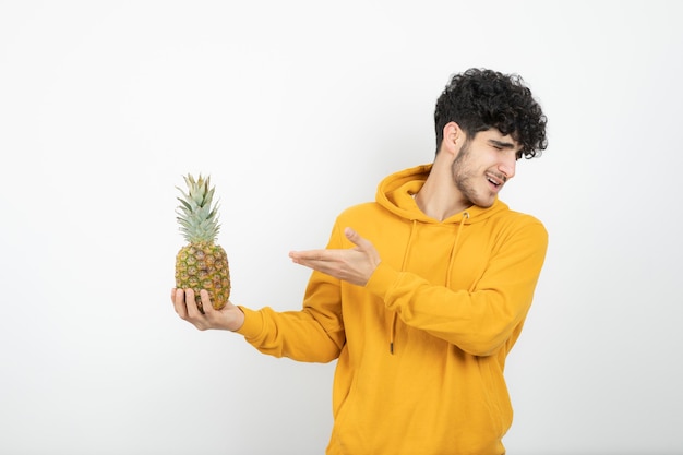 Retrato de un joven morena de pie y sosteniendo la piña.