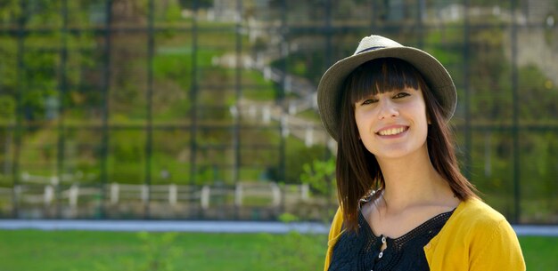 Retrato de joven morena con sombrero de verano en el parque