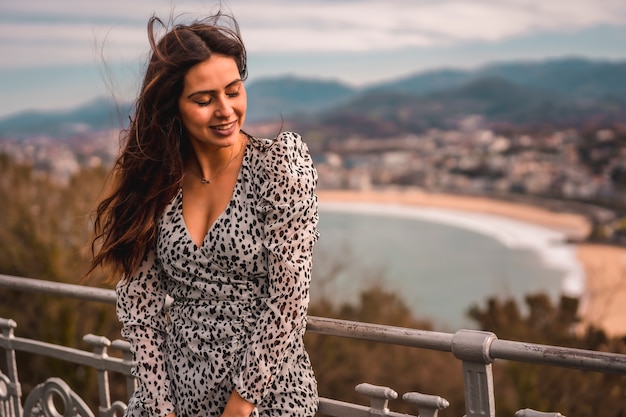 Retrato de una joven morena con un vestido corto blanco en el mirador de la ciudad de San Sebastián