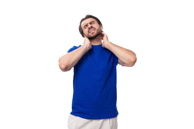Foto retrato de un joven moreno con una barba bien cuidada vestido con una camiseta azul en un blanco