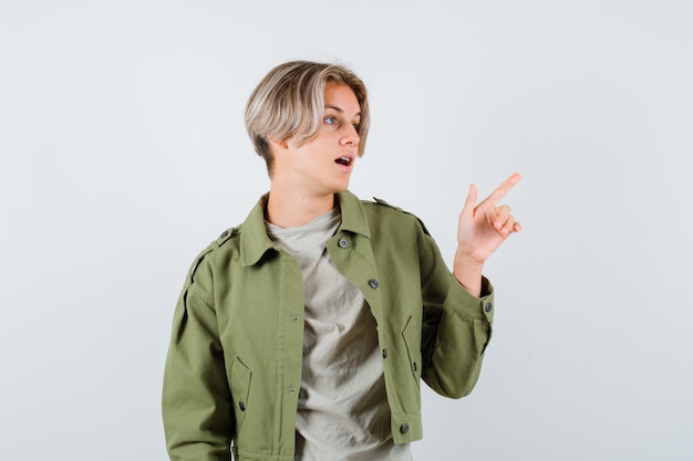 Retrato de joven muchacho adolescente apuntando a la esquina superior derecha de la camiseta