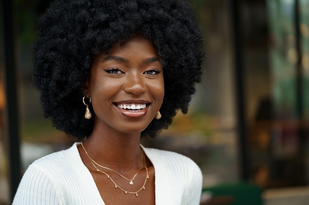 retrato, de, joven, mujer africana, con, peinado, sonriente, en, urbano, plano de fondo