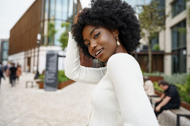 retrato, de, joven, mujer africana, con, peinado, sonriente, en, urbano, plano de fondo