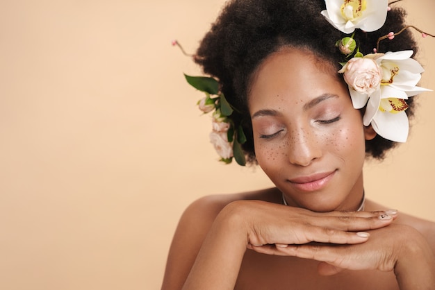 Retrato de joven mujer afroamericana pecosa semidesnuda con flores en el pelo