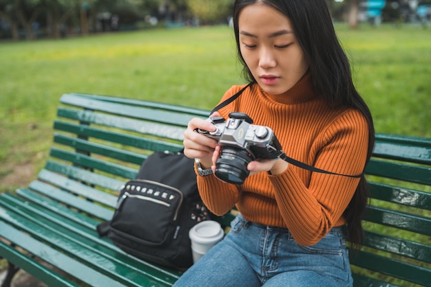 Retrato de joven mujer asiática con una cámara digital profesional en el parque al aire libre. Concepto de fotografía.