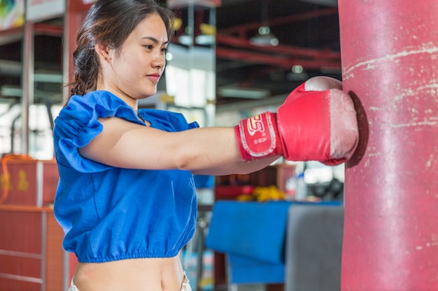 Retrato de joven mujer asiática con guantes de boxeo practicando boxeo en el gimnasio.