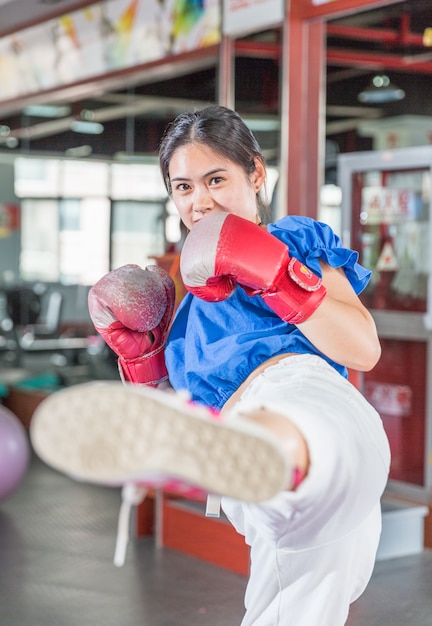 Retrato de joven mujer asiática con guantes de boxeo practicando boxeo en el gimnasio.