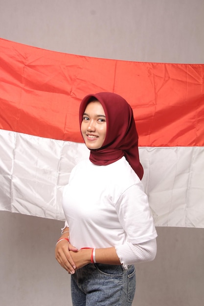 Foto retrato joven mujer asiática en hiyab de pie con entusiasmo celebrando el día de la independencia de indonesia039s