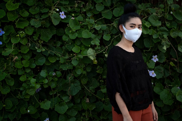 Retrato joven mujer asiática de pie y con una máscara de moda