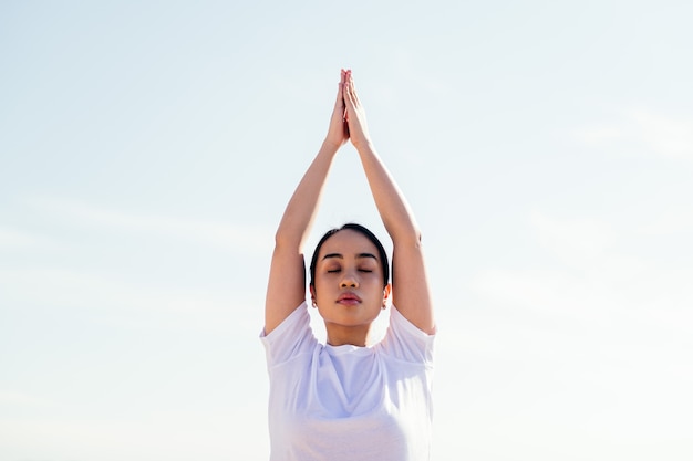 Retrato de una joven mujer asiática relajante mientras practica yoga con los ojos cerrados, concepto de espiritualidad y relax