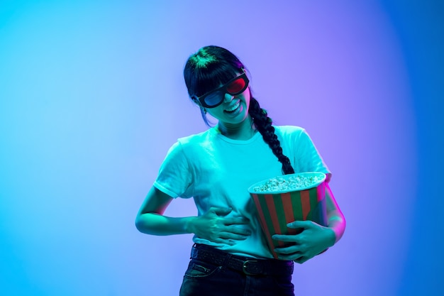 Retrato de joven mujer asiática sobre fondo de estudio azul-púrpura degradado en luz de neón