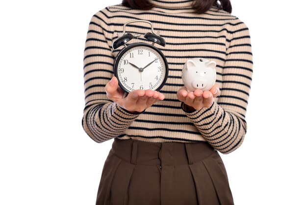 Retrato de joven mujer asiática uniforme casual sosteniendo alcancía blanca y reloj despertador aislado sobre fondo blanco Concepto de dinero de ahorro financiero y bancario