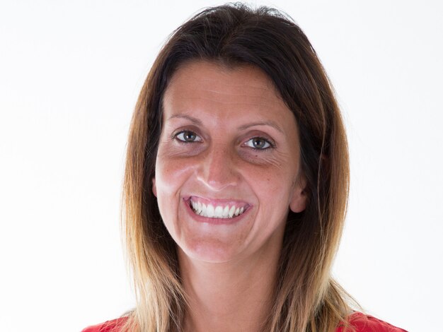 Retrato de joven mujer bastante positiva sonriendo mirando a la cámara sobre fondo blanco.