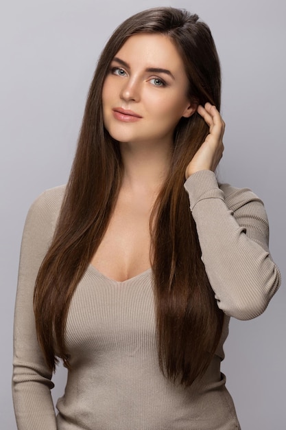 Retrato de joven mujer bonita con un hermoso cabello largo sobre fondo gris