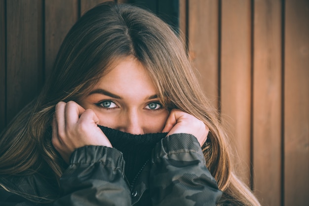 Retrato joven mujer bonita en invierno en una cabaña de troncos en la nieve.