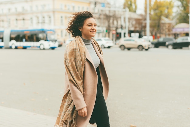 Retrato de joven mujer casual vistiendo un bonito abrigo y caminando por las calles de la ciudad