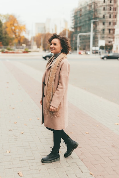 Retrato de joven mujer casual vistiendo un bonito abrigo y caminando por las calles de la ciudad