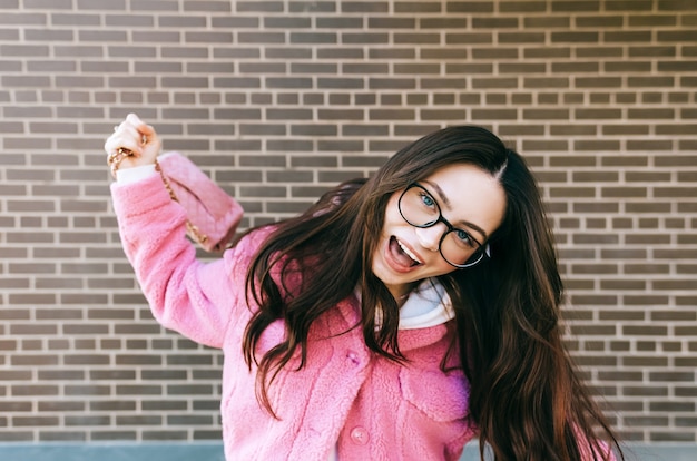 Retrato de joven mujer caucásica alegre con cabello morena en anteojos.