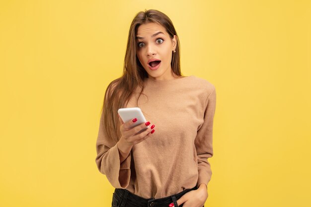 Retrato de joven mujer caucásica con emociones brillantes aisladas sobre fondo amarillo studio