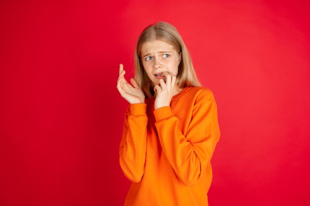 Retrato de joven mujer caucásica con emociones brillantes aisladas sobre fondo rojo de estudio