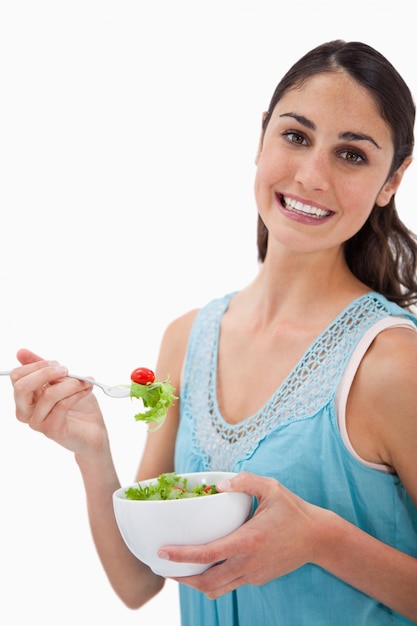 Retrato de una joven mujer comiendo una ensalada