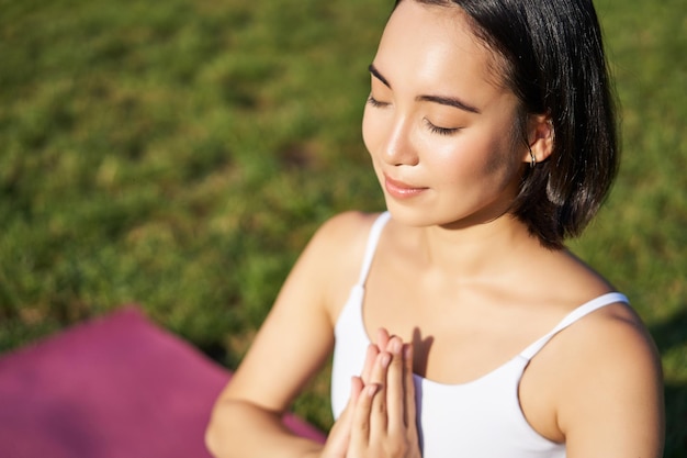 Foto retrato de una joven mujer consciente que practica yoga haciendo ejercicio inhalando y exhalando aire fresco en el parque sitt