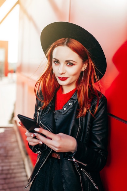 Retrato de una joven mujer elegante sosteniendo un teléfono inteligente de cerca