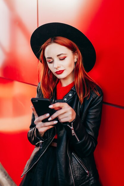 Retrato de una joven mujer elegante sosteniendo un teléfono inteligente de cerca