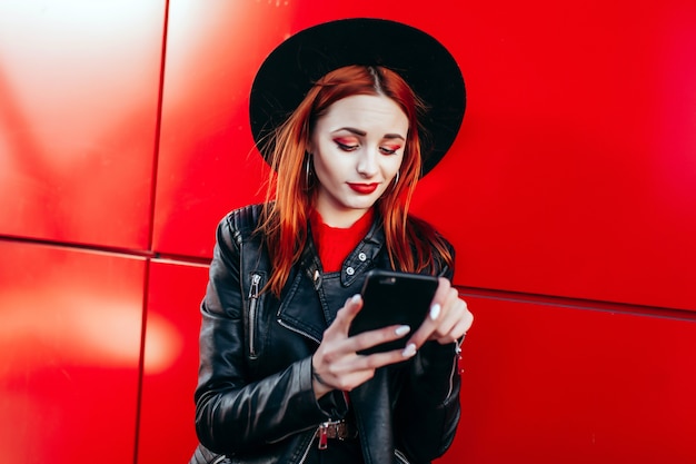 Retrato de una joven mujer elegante sosteniendo un teléfono inteligente de cerca