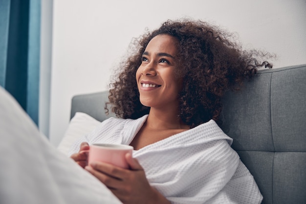 Retrato de una joven mujer encantadora con una sonrisa radiante recostado en la cama