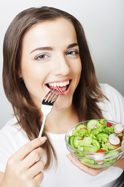 Retrato de joven mujer feliz comiendo ensalada