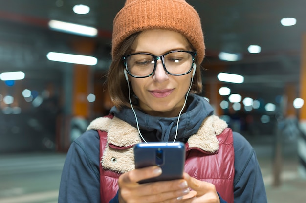 Retrato de una joven mujer feliz escuchando música en un teléfono inteligente