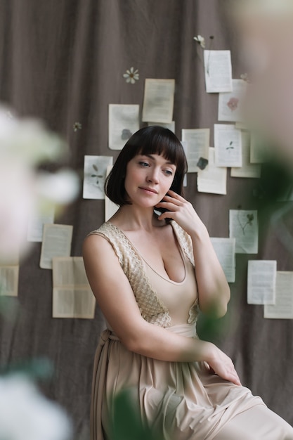 Retrato de una joven mujer hermosa con cabello oscuro posando detrás de flores