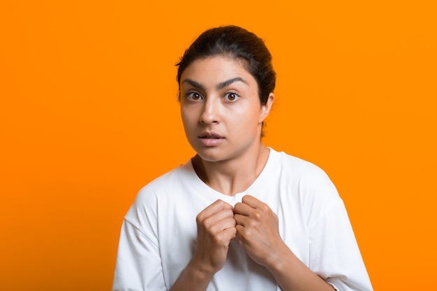 Retrato de joven mujer india adulta asustada sorprendida en camiseta