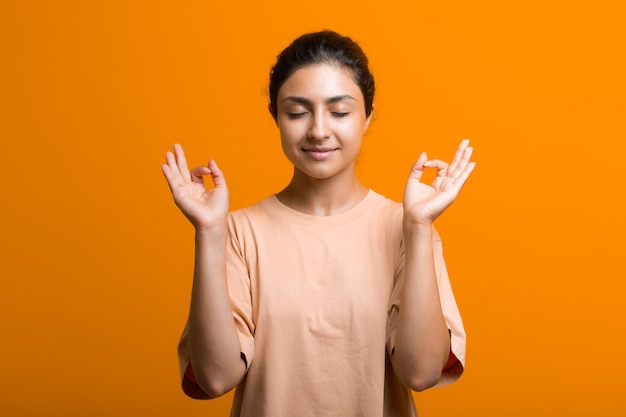 Retrato de joven mujer india adulta meditando zen como con signo ok mudra gesto con los ojos cerrados