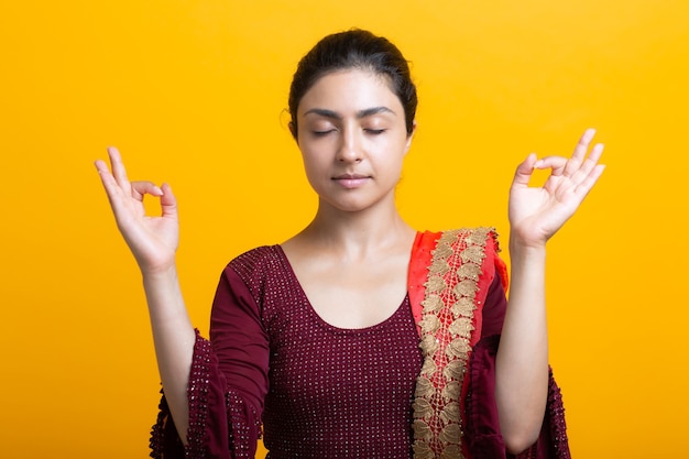 Retrato de joven mujer india adulta en sari meditar zen como con signo ok gesto mudra