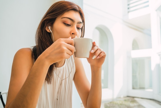 Retrato de joven mujer latina disfrutando y bebiendo una taza de café en la cafetería. Concepto de estilo de vida.